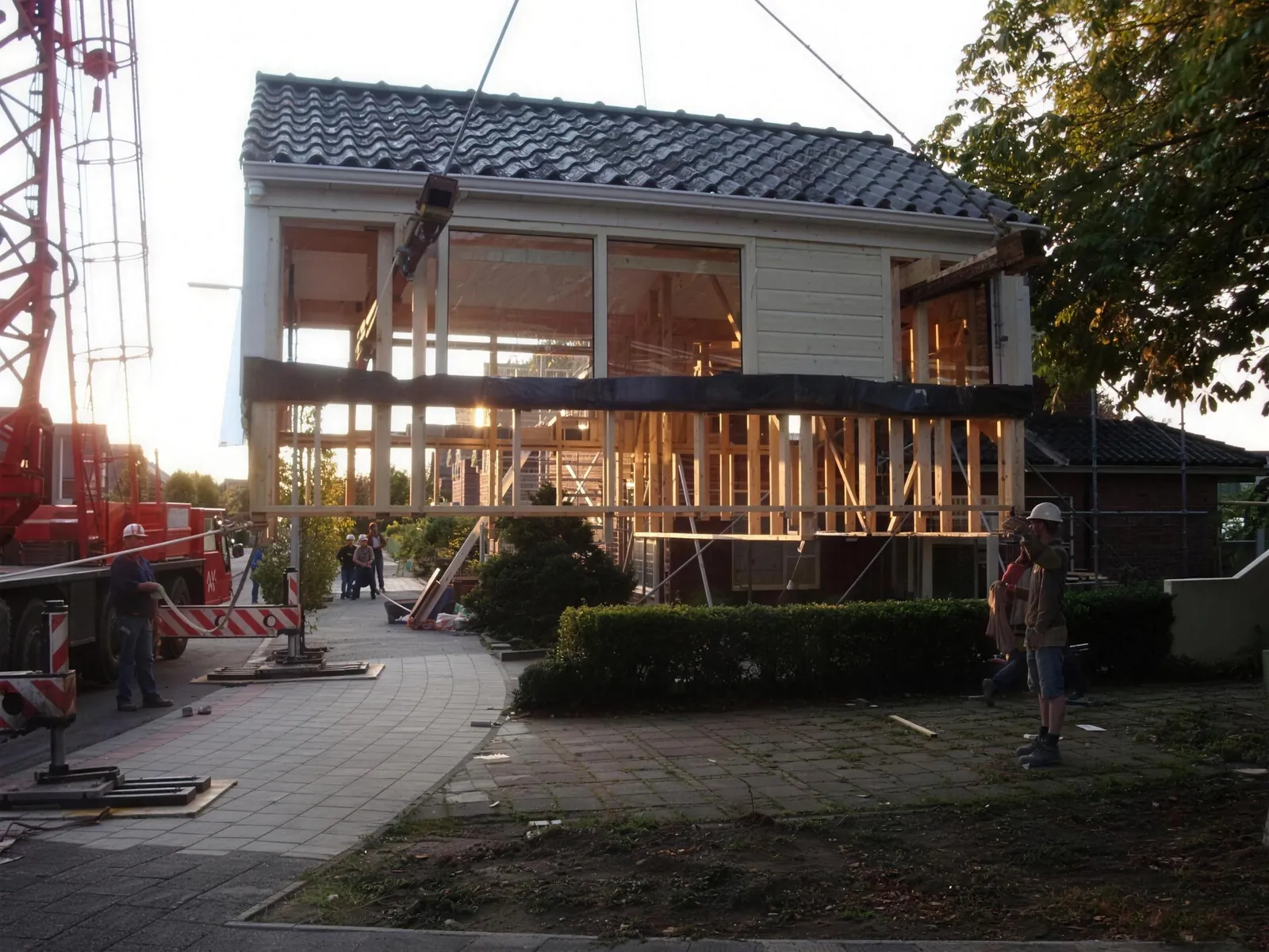 Een kraan plaatst in de avond een prefab dakopbouw uit de werkplaats van HB Bouw