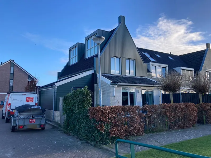 Woning in Sijbekarspel met de groene aanbouw links, bus en aanhanger van HB Bouw op de oprit