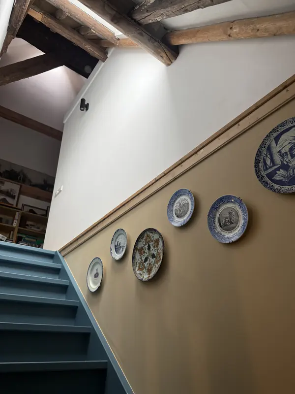 Trap naar boven onder oude houten balken, met wandborden langs de trap