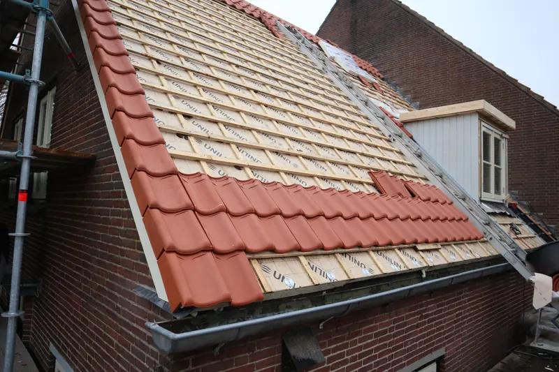 Dakvlak in Obdam met isolatieplaten, panlatten en de eerste rijen rode pannen, dakkapel rechts