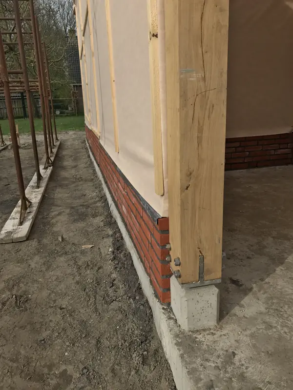 Eiken staander op een betonpoer met stalen anker naast de gemetselde plint, Hoogwoud