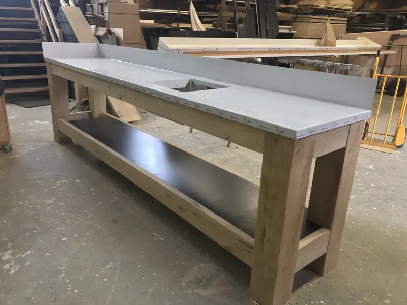 Eiken meubel met grijs werkblad, uitsparing en spatrand in de werkplaats, project hertenkamp Hoogwoud