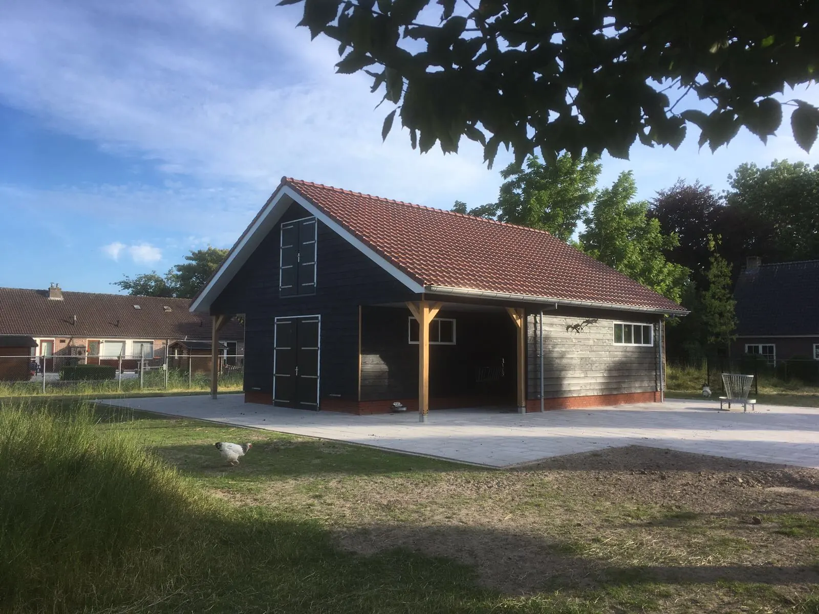 Schuur bij het hertenkamp in Hoogwoud van zwarte delen met roodbruine pannen en overkapping op eiken staanders