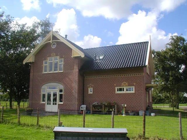 Woonhuis in Opmeer met tuindeuren onder een rondboog, gele sierbanden en een dakkapel in het pannendak