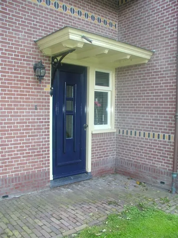 Blauwe voordeur onder een afdak op smeedijzeren consoles, woonhuis in Opmeer