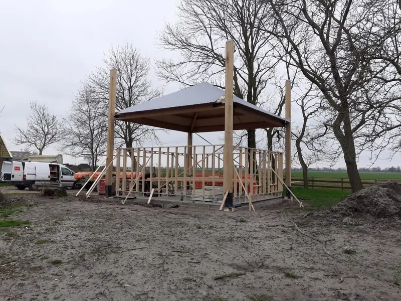 Houtskelet van de berging onder de kap op vier palen, kapschuur in Hoogwoud in aanbouw