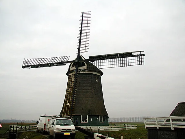 Molen Nieuw Leven in de Wogmeer met riet gedekt lijf en twee bedrijfsbussen ervoor
