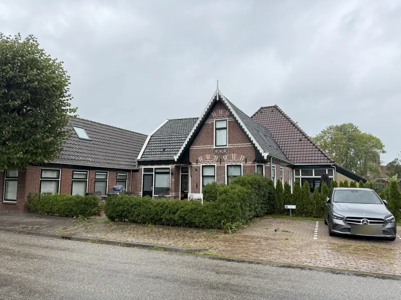 Complex van het voormalige café met voorhuis, lange vleugel met dakramen en hoge kap