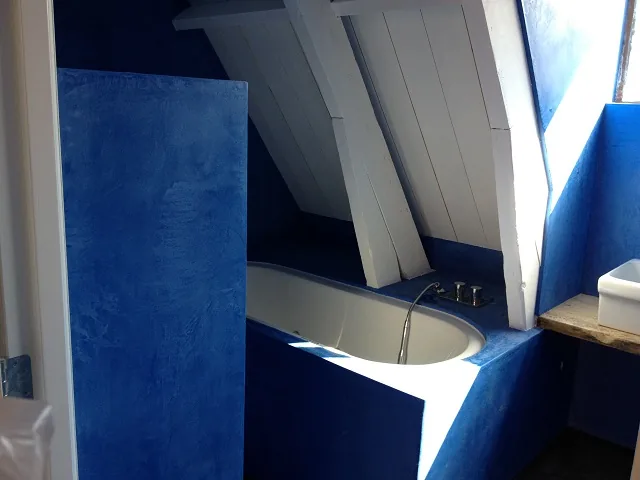Ligbad tussen de witte balken onder de schuine kap, blauwe wanden, badkamer in Alkmaar