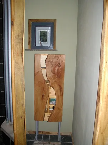 Radiatorombouw van een plank met natuurlijke rand tussen ruw houten stijlen