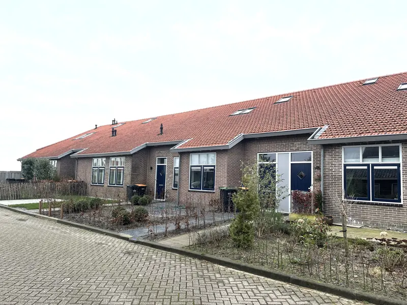 Woningen in het voormalige verenigingsgebouw in Hoogwoud met blauwe voordeuren, dakramen en jonge voortuinen