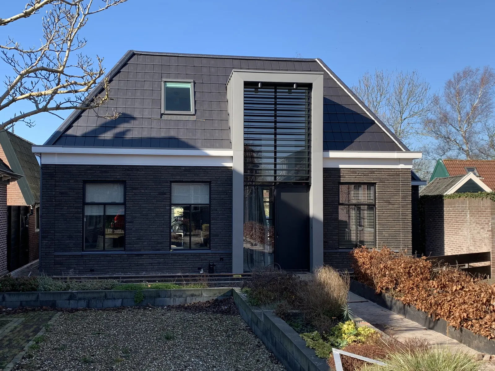 Modern woonhuis in Broek op Langedijk met lichtgrijze kaders, zwarte lamellen en donkere baksteen