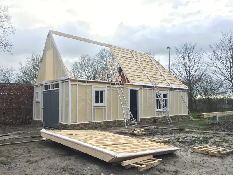 Schuur in Spanbroek in aanbouw met houtskelet, dakbeschot, panlatten en grijze deuren