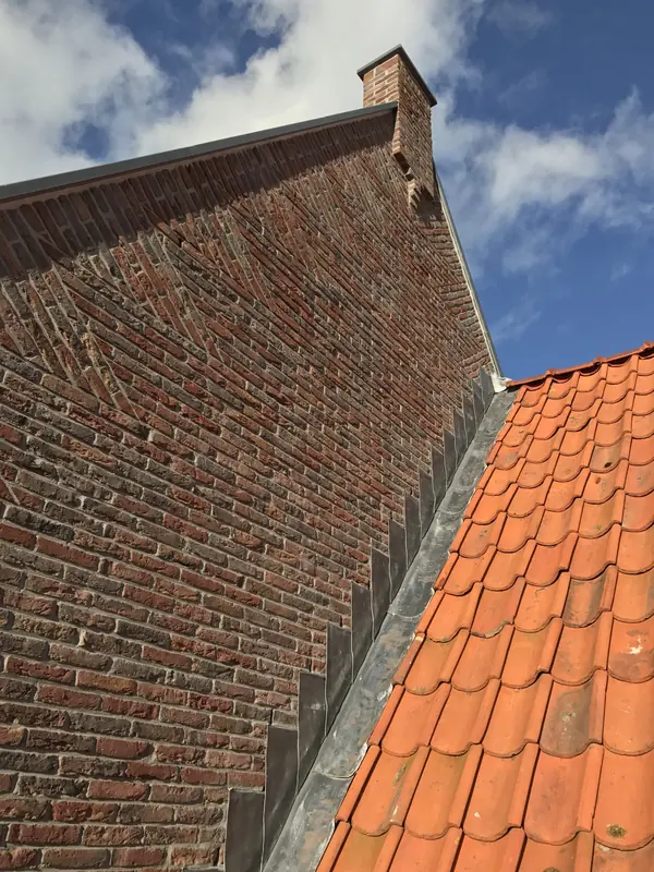 Vlechtwerk in de topgevel met schoorsteen, loodslabben en oranje pannen
