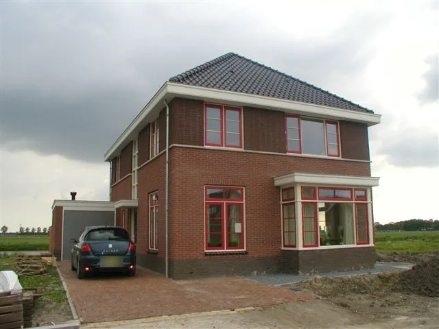 Woonhuis in Wognum van rode baksteen met rode kozijnen, witte daklijst en erker